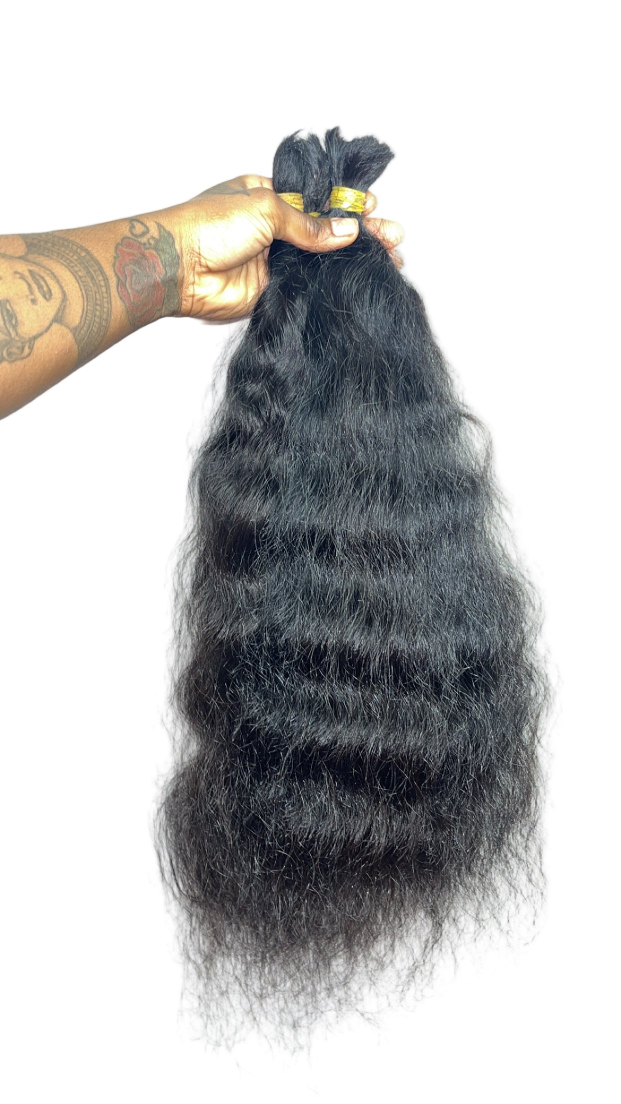 Black hair bundle held by a hand with visible tattoos on a white background