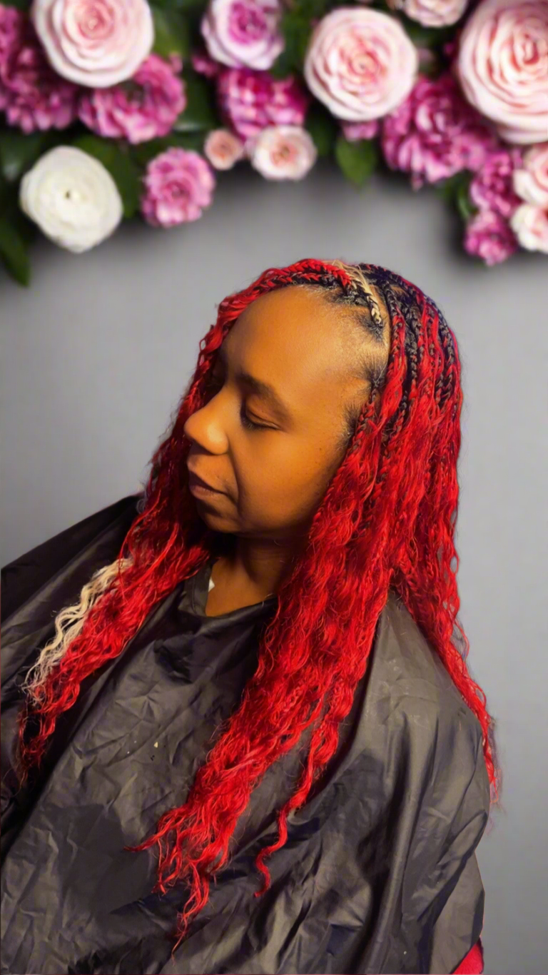Person with red hair and black jacket in front of pink flowers luxury braiding hair 